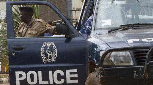 A Ugandan police officer stands outside of his vehicle.
