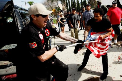 A Ku Klux Klansman, left, fights a counter protester for an American flag after members of the KKK tried to start a "White Lives Matter" rally at Pearson Park in Anaheim on Saturday, Feb. 27, 2016. 