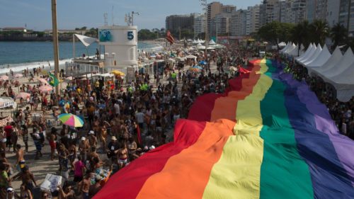 Parade goers carrying rainbow flag at 2016 Rio Pride Parade. Rio Pride Parade