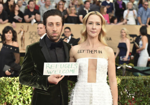 Simon Helberg, left, and Jocelyn Towne display protest signs against the U.S. policy of temporarily barring refugees and citizens of seven predominantly Muslim countries, at the 23rd annual Screen Actors Guild Awards at the Shrine Auditorium & Expo Hall on Sunday, Jan. 29, 2017, in Los Angeles.