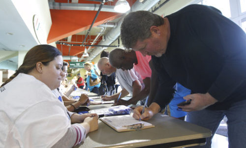 Volunteer Lily Miranda, left, watches as Jim Eriksen, right checks in before a town hall meeting called "The Resistance Training" hosted by the American Civil Liberties Union, Saturday, March 11, 2017, in Coral Gables, Fla. The ACLU is launching a nationwide training event to make people aware of their rights as protesters. Organizers say the event Saturday at a sports arena on the University of Miami campus is being livestreamed to locations in all 50 states.
