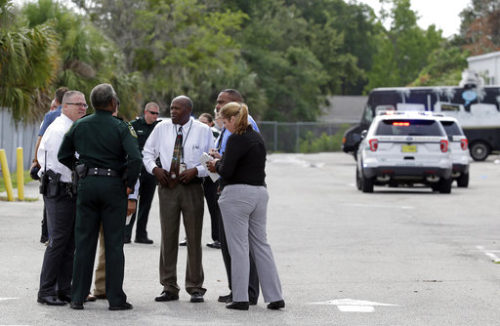 Authorities confer near the scene of a shooting where they said there were multiple fatalities in an industrial area near Orlando, Fla., Monday, June 5, 2017. The Orange County Sheriff's Office said on its official Twitter account that the situation has been contained.