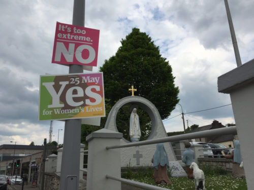 Cork, Ireland - Yes and No posters for the 25th of May referendum regarding the issue of abortion, near the Fatima and the three little shepherds statue in Blackpool. Two signs hang on a lamppost before a Christian statue. One says "Vote Yes." The other "Vote No."
