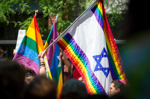 JUNE 25, 2017: Jewish participants wave Israeli Star of David rainbow flags as the Gay Pride Parade passes through Greenwich Village. JUNE 25, 2017: Jewish participants wave Israeli Star of David rainbow flags as the Gay Pride Parade passes through Greenwich Village.
