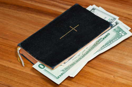 A Christian Bible stuffed with dolllars