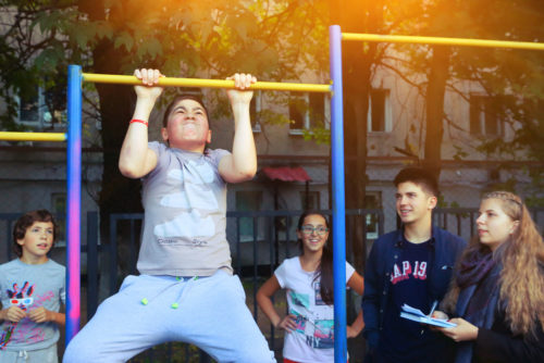 Unidentified school kids on outdoor sport pull up exercises competition in school yard in Moscow