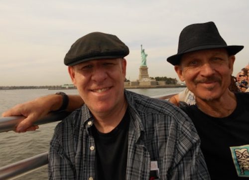 Two men on a boat with the Statue of Liberty in the background