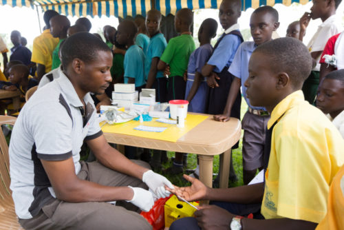 Nkokonjeru, Uganda June 22 2017: A health worker tests a boy for HIV. Nkokonjeru, Uganda June 22 2017: A health worker tests a boy for HIV.