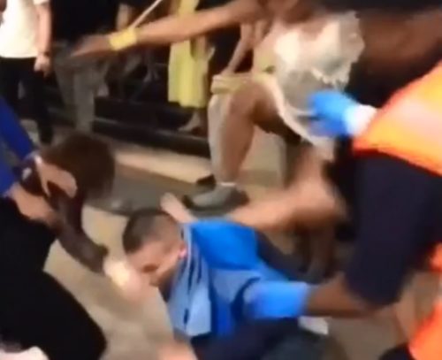 A woman's leg is stomping on someone on the ground while a crowd watches