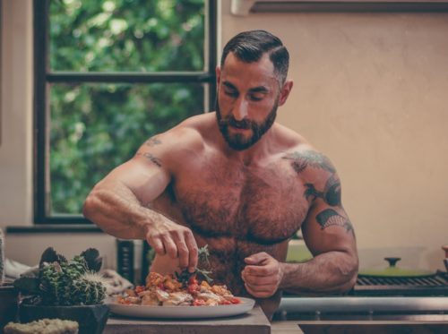 The Bear-Naked Chef, shirtless and cooking in a kitchen