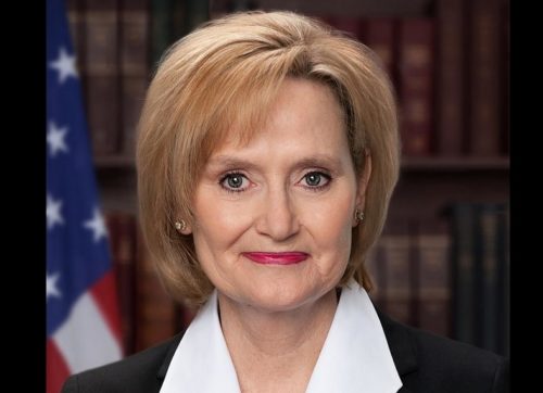 Cindy Hyde-Smith in front of books and an American flag