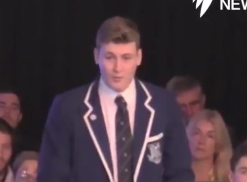 A boy in a blazer at a lectern.
