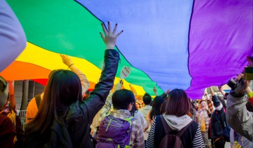 Marchers at the 2014 Hong Kong Pride. Backs of people marching and holding a rainbow banner