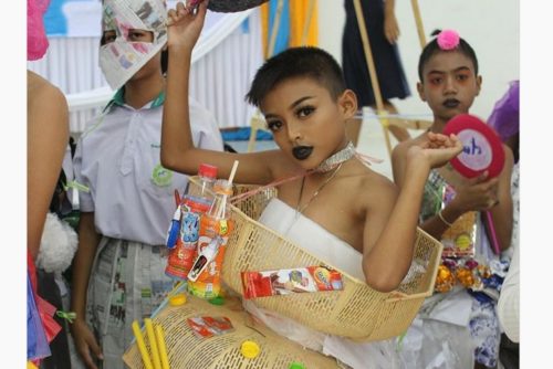 A boy wearing plastic baskets and various food items as drag