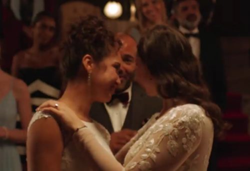Two women dancing, a man in the background