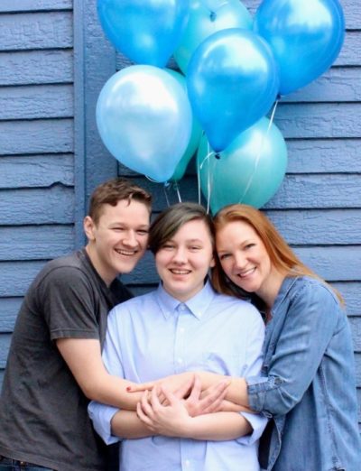 Green family in front of blue balloons