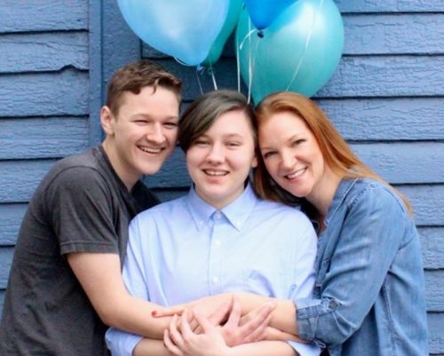 Green family in front of blue balloons