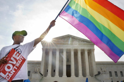 Carlos McKnight of Washington, waves a flag in support of gay marriage outside of the Supreme Court in Washington, Friday June 26, 2015. A protestor with a rainbow flag outside the Supreme Court