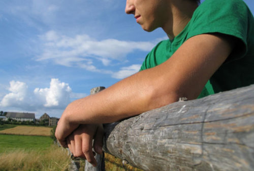 A young person looking forlorn outdoors.