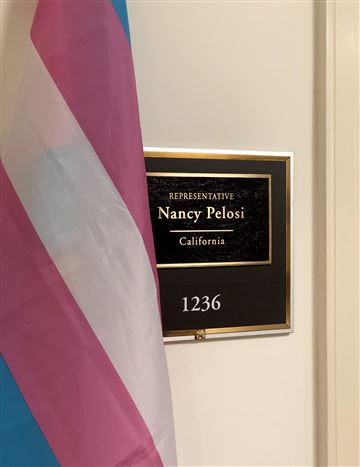 Transgender flag next to a sign for the office of Nancy Pelosi