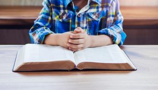 A child praying over a Bible