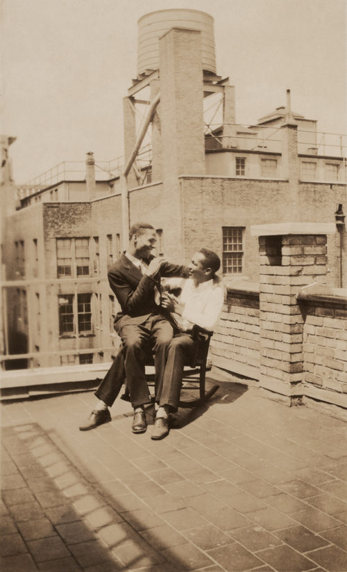 A Black couple pose in a rocking chair