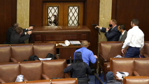 U.S. Capitol Police with guns drawn stand near a barricaded door as protesters try to break into the House Chamber at the U.S. Capitol on Wednesday, Jan. 6, 2021, in Washington.