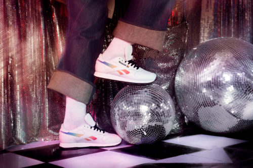 Model wearing Reebok Pride Club C sneakers while stepping on a disco ball