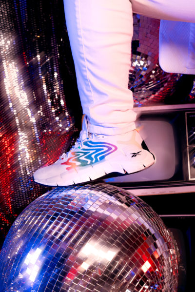 Model wearing Reebok Zig Kinetica II sneakers while stepping on disco ball