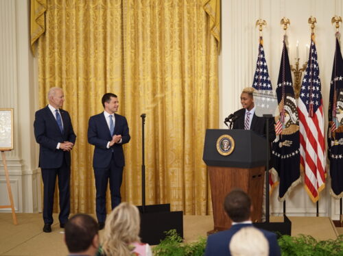 President Joe Biden (left) and Transportation Secretary Pete Buttigieg applaud 16 year-old Ashton Mota as Mota speaks to the crowd assembled in the White House East Room