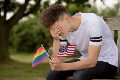 Depressed teenager with american and rainbow flags